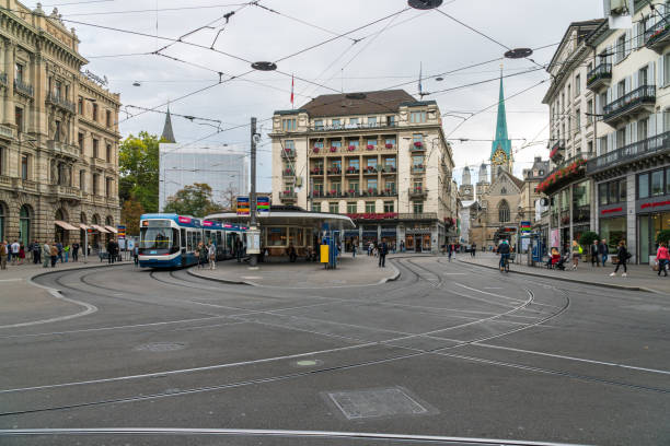 Paradeplatz square in Zurich with its famous tram station in front of the Savoy Hotel and Fraumünster church Zurich, Switzerland - October 6, 2018: People visiting the Paradeplatz square with its famous tram station, Savoy Hotel and a view to Fraumünster church. A landmark and famous tourist destination. switzerland zurich architecture church stock pictures, royalty-free photos & images