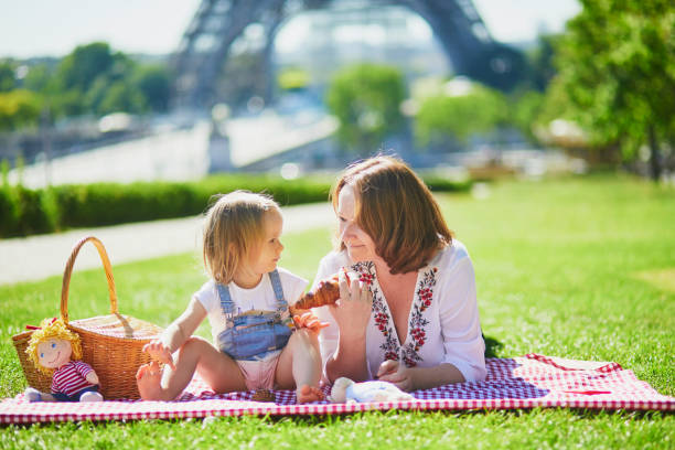 giovane donna con bambina che fa un picnic vicino alla torre eiffel a parigi - family eiffel tower baby vacations foto e immagini stock