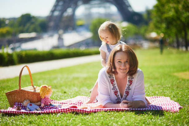 giovane donna con bambina che fa un picnic vicino alla torre eiffel a parigi - family eiffel tower baby vacations foto e immagini stock