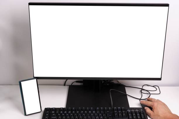 Close up macro view of hand man using computer monitor with mockup image blank screen and cell phone with white background for advertising text.