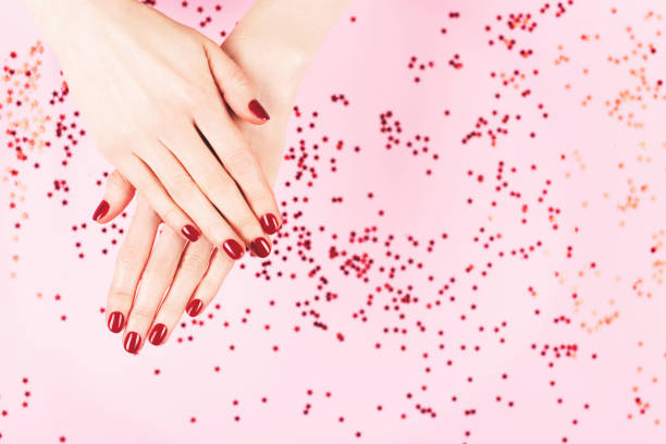 istock Two woman hands and falling confetti on pink background. 1245176201