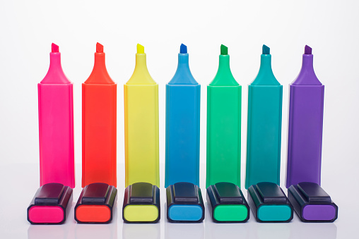 Office supplies concept. Photo of multicolored highlighter set with caps beside isolated on white background
