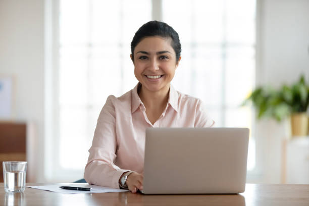 istock Young smiling indian woman sitting at table with computer. 1245196311