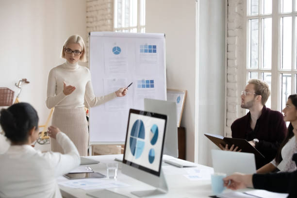 Millennial speaker in eyeglasses explaining marketing strategy to colleagues.
