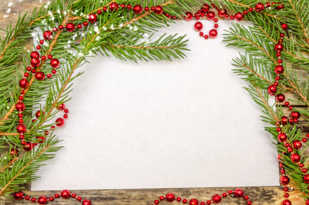 istock White leaf on wooden background with Christmas tree branches and red beads close up with copy space. Beautiful Christmas background or greeting card 1245202641