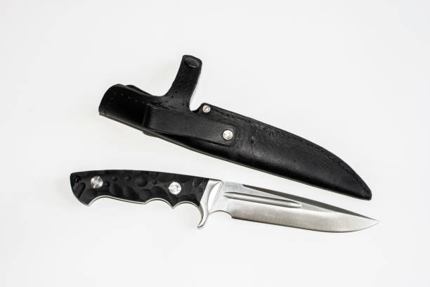 istock A large knife with a black handle and a sharp blade. Next to it is a black leather holster case with a button buckle. Hunting, butchering. On white background. 1245214857