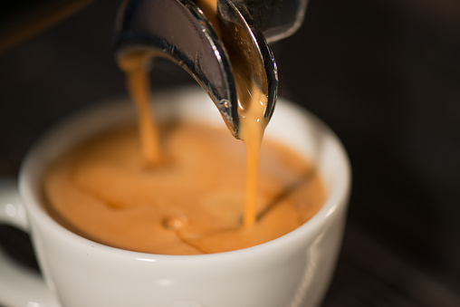 espresso coffee in the white cup under the espresso machine