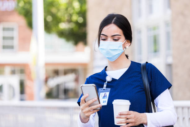 istock Young nurse with protective mask stops to check phone 1245239407