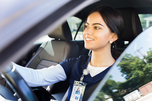 A confident female healthcare professional drives to work in a hospital or medical clinic.