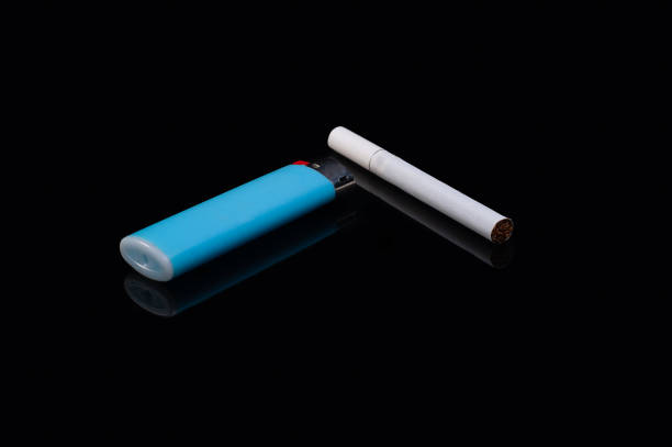 istock one white filter cigarette and a plastic gas blue lighter on an isolated black background with reflection 1245251595