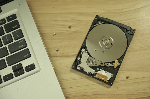 Close up of uncovered broken 2.5 inch hard drive with unreadable data. An illustrated concept of repairing laptop and its hard drive.