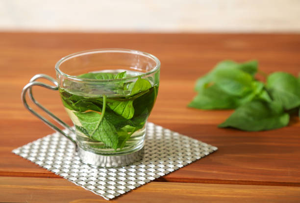 Pictured a cup of mint tea in a wooden background.