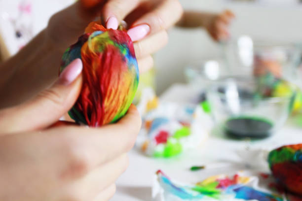 istock wrap an egg in a napkin and paint for Easter, hand made abstract painting while you are sitting at home, a cozy house, art therapy, blurred background 1245286269