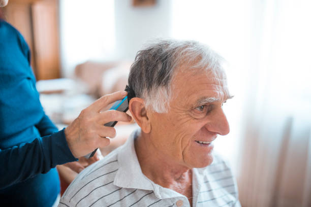Woman cutting senior man's hair with electric razor at home during coronavirus quarantine Woman cutting senior man's hair with electric razor at home during coronavirus quarantine cutting hair stock pictures, royalty-free photos & images