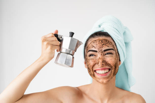 얼굴에 커피 스크럽 마스크를 적용 하는 젊은 웃는 여자 - 집에서 건강 한 피부 관리 스파 데이 를 가진 행복 한 여자 - 대체 자연 각질 제거 치료 및 사람들 라이프 스타일 개념 - 각질제거 스크러브 뉴스 사진 이미지