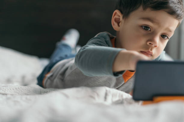 istock selective focus of cute boy touching smartphone while lying in bed 1245324305
