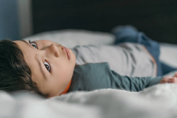 istock selective focus of thoughtful boy lying on bed at home and looking away 1245324312