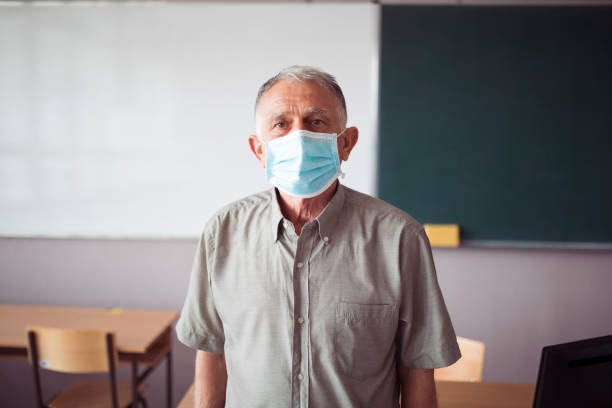 Portrait of senior teacher wearing a face mask during corona virus crisis stock photo