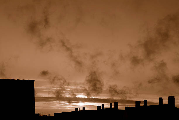 Moody and smoky sunset sky over rooftops and chimneys. 