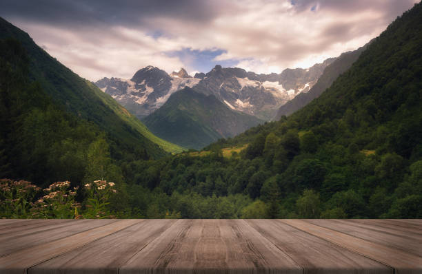 View of the Caucasus mountain range in Racha, Georgia. Summer beautiful background with empty wooden table. Natural template landscape stock photo