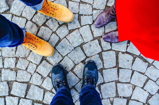 the feet and shoes of three people. three people standing outside on autumn day