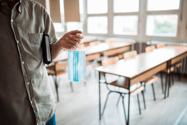 istock College professor holding face mask in an empty classroom 1245337495