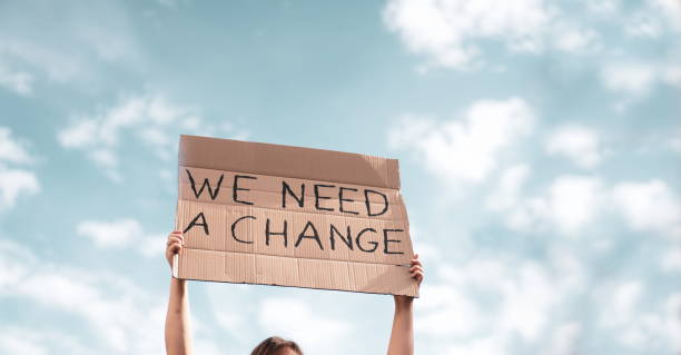 woman holding a banner of 'we need a change'. problem in ecology, environment, global warming, industrial influence, climate emergency - protests human rights imagens e fotografias de stock