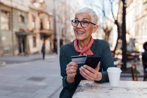 Happy senior woman using a smart phone and a credit card