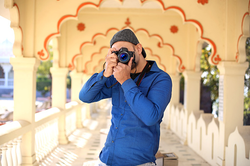 Young handsome Indian professional photographer taking a picture in The Gommatagiri Digambar Jain Temple during day time, Indore, Madhya Pradesh, India.