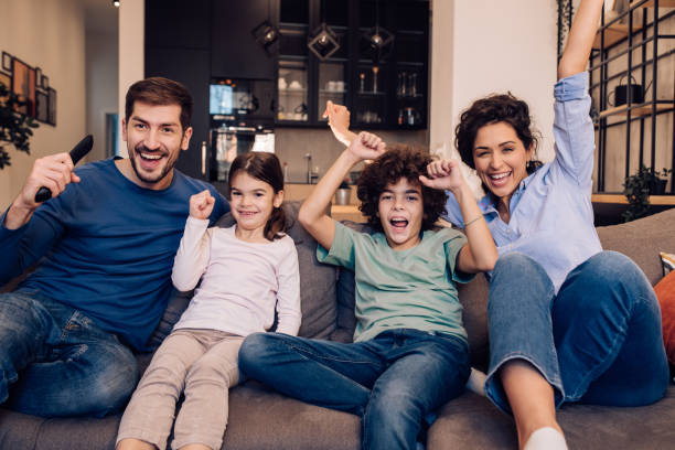 istock Kids watching TV with their parents, cheering and having fun 1245463815