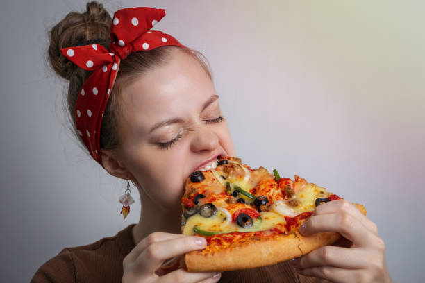young caucasian woman girl biting devouring a big pizza slice. hunger concept - bite size imagens e fotografias de stock