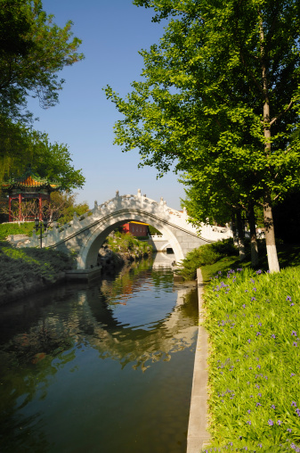 A white marble arch bridge over the Beijing  Park canal with a Pagoda in the background