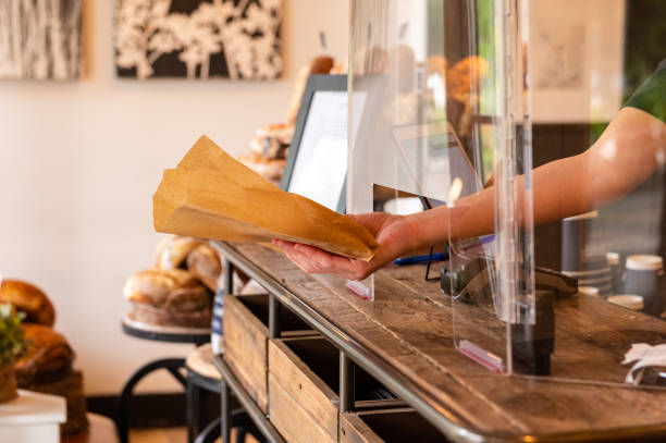istock Entrepreneur passing baked goods through a plexi guard for reopening 1245544593