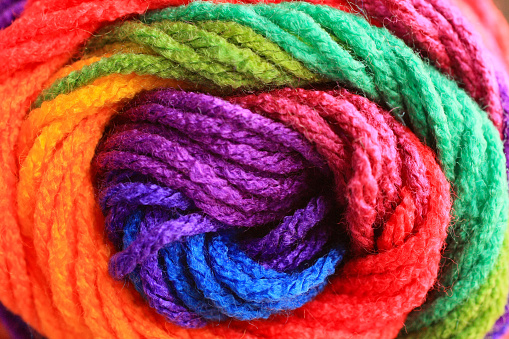 rainbow roll of yarn close up macro. With purple blue orange yellow and green mixed together