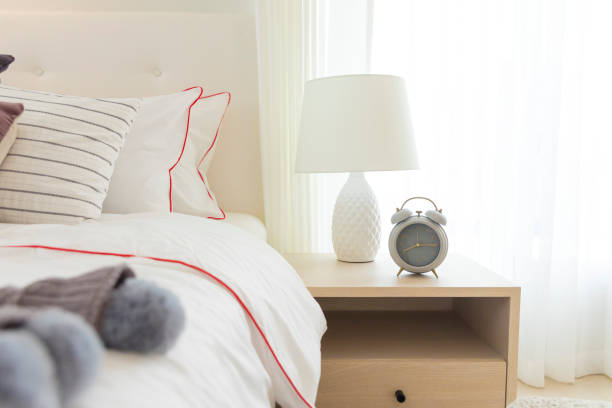 istock Alarm clock on the table beside white cozy bed in bedroom. 1245612718