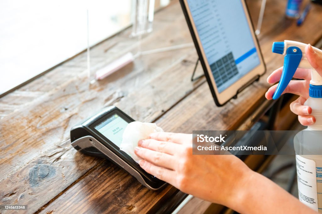 Sanitizing a contactless payment terminal for COVID safety Safety protocol for reopening during the COVID-19 pandemic. Cleaning Stock Photo