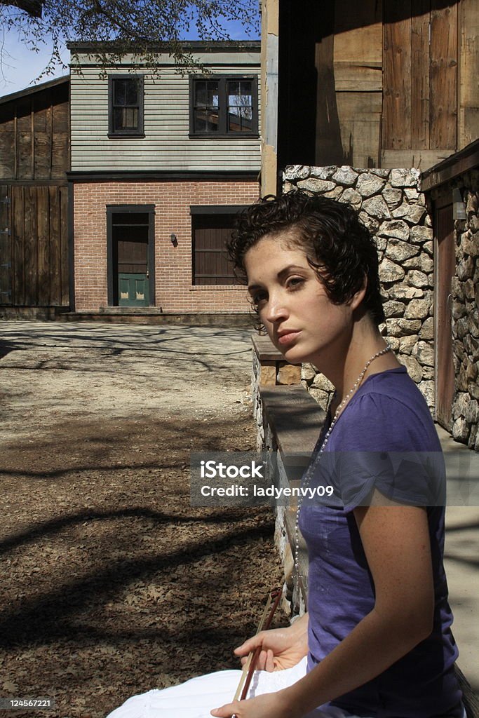 Smiling in the sun Cute girl with short curly brown hair sitting in a ghost town Adult Stock Photo