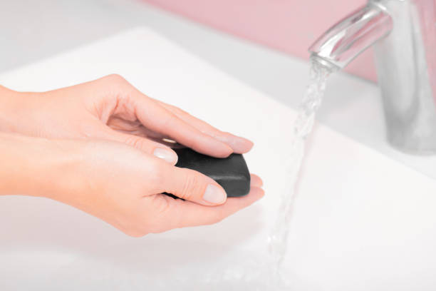 istock Woman washing hands with black soap over sink 1245703480