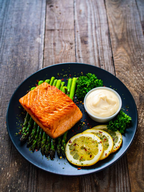 istock Fried salmon steak and asparagus on wooden table 1245713753