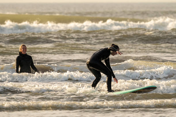 istock Friends learn to surf in water shallows 1245718012