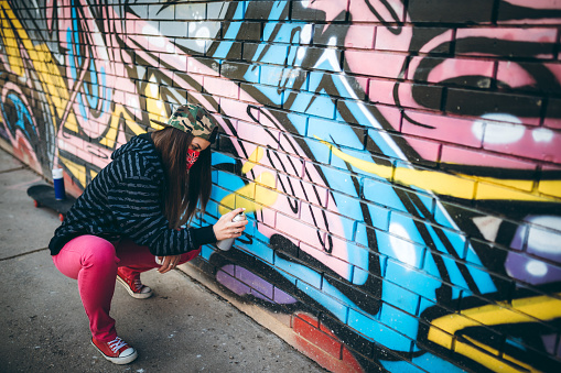 Graffiti female artist painting outdoor.