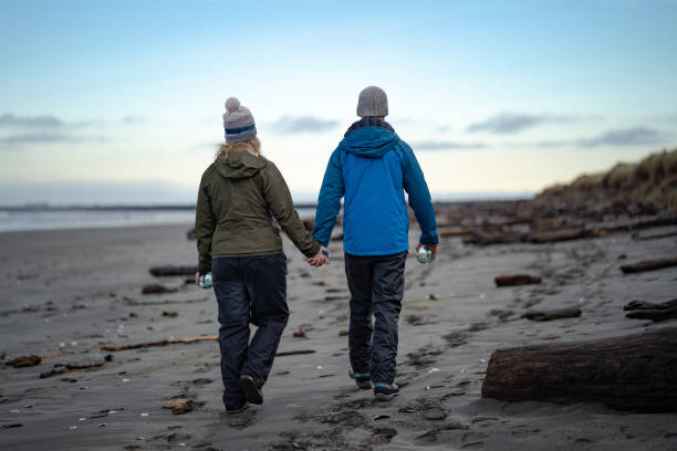 istock Young couple walk across beach holding crystal spheres 1245729934