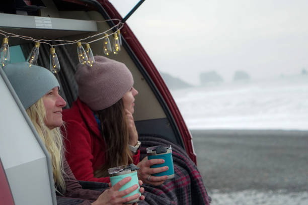 due donne si rilassano nel bagagliaio della loro auto con bevande calde - china sea foto e immagini stock