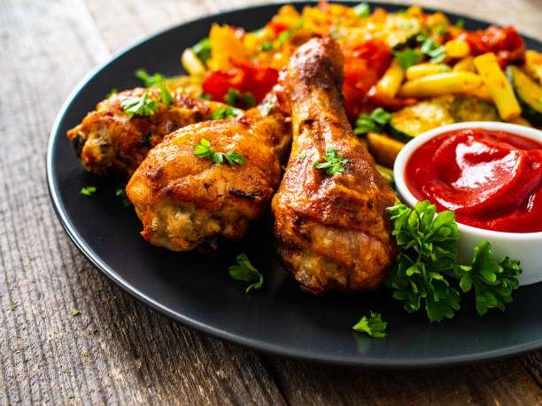 istock Roast chicken drumsticks and vegetables served on wooden table 1245749847