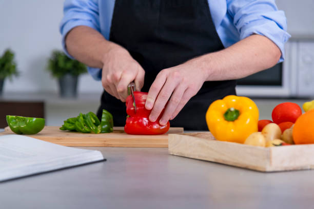 istock a young male cutting a red bell pepper on a cutting board surrounded by assorted vegetables 1245772700