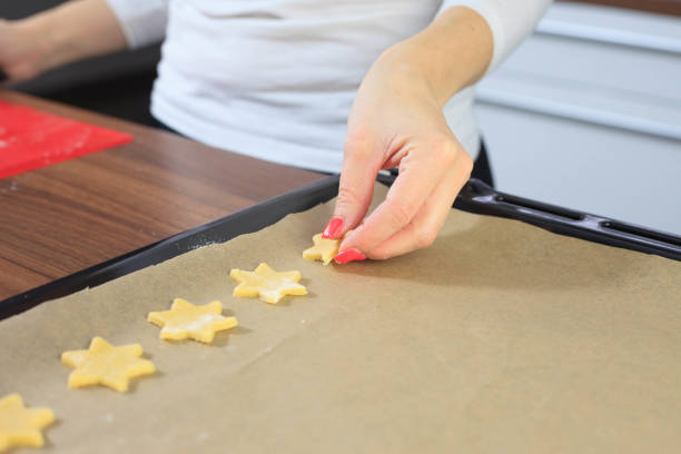 istock Young hands giving the ginger stars to baking sheet (color toned image) 1245803368