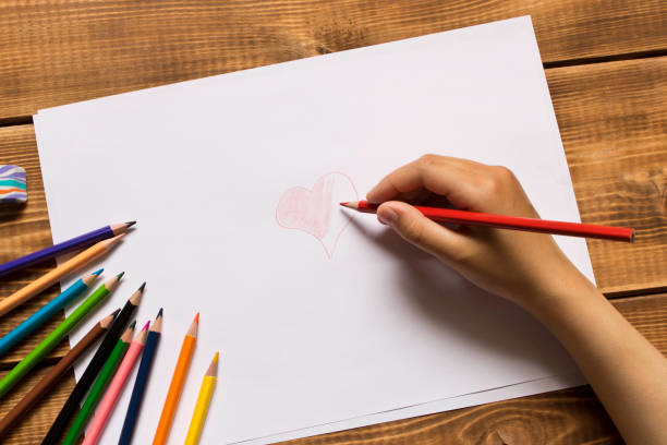 The girl draws with colored pencils. Close up