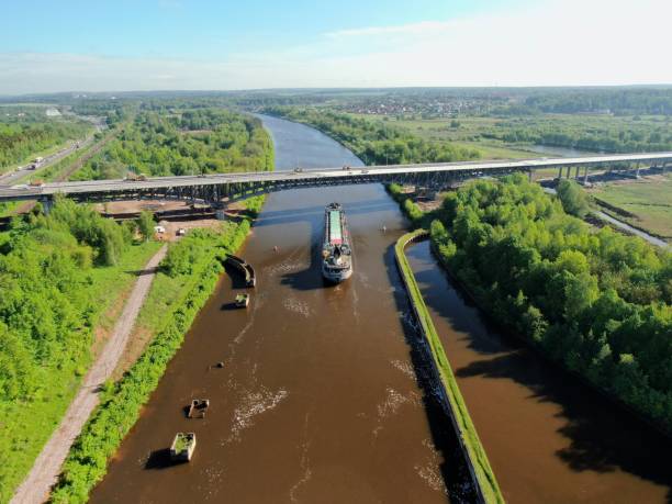 istock Beautiful panoramic landscape from high altitude cargo commercial ship sails down river surrounded by green forest in summer with sunny day 1245811902