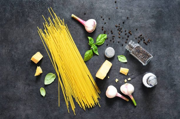 istock Ingredients for making pasta. Raw spaghetti with basil on a black background. View from above. 1245831345