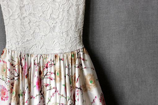 Dress with floral print close-up on a gray background. Women's clothing. White top dresses. Flower skirt